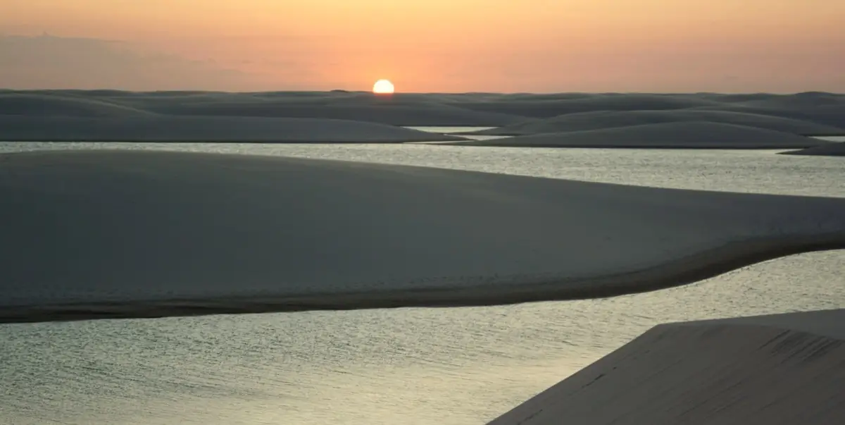 Sol se pondo atrás das dunas e refletindo na lagoa